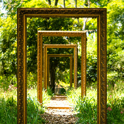 photo illustration of several picture frames arranged as doors that open into each other in a garden, by Declan Sun for Unsplash.