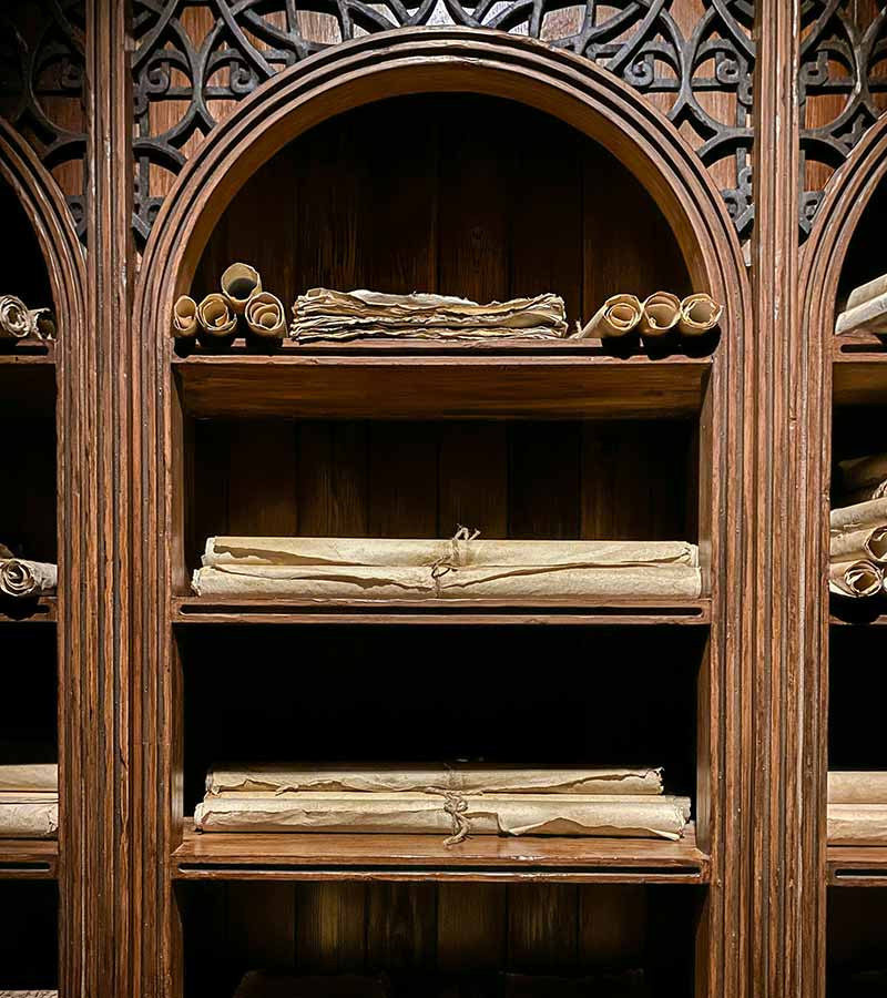 photo of wooden shelf with ancient manuscripts, by Max Tcvetkov for Unsplash.